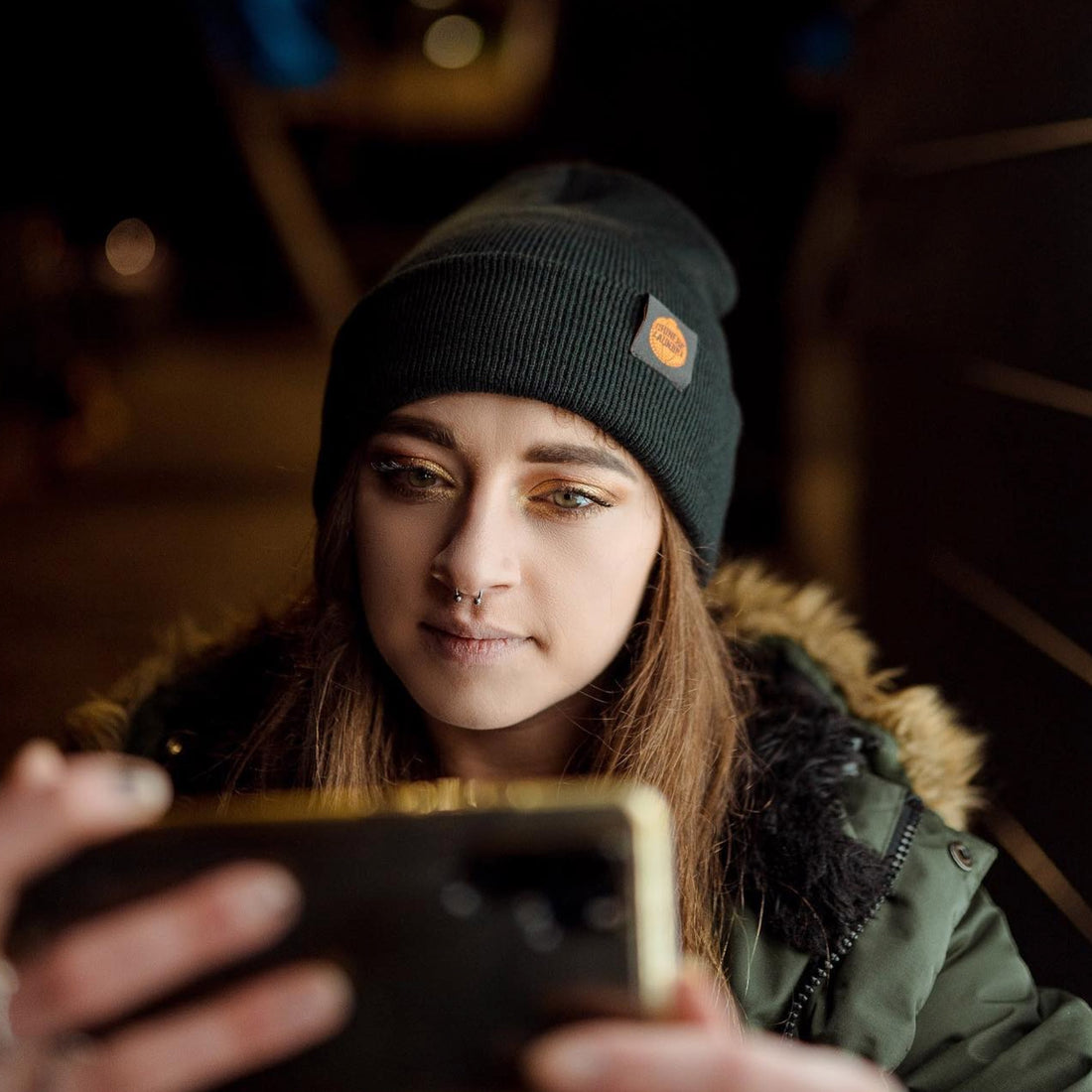 Female waring Chinese Laundry beanie looking at phone